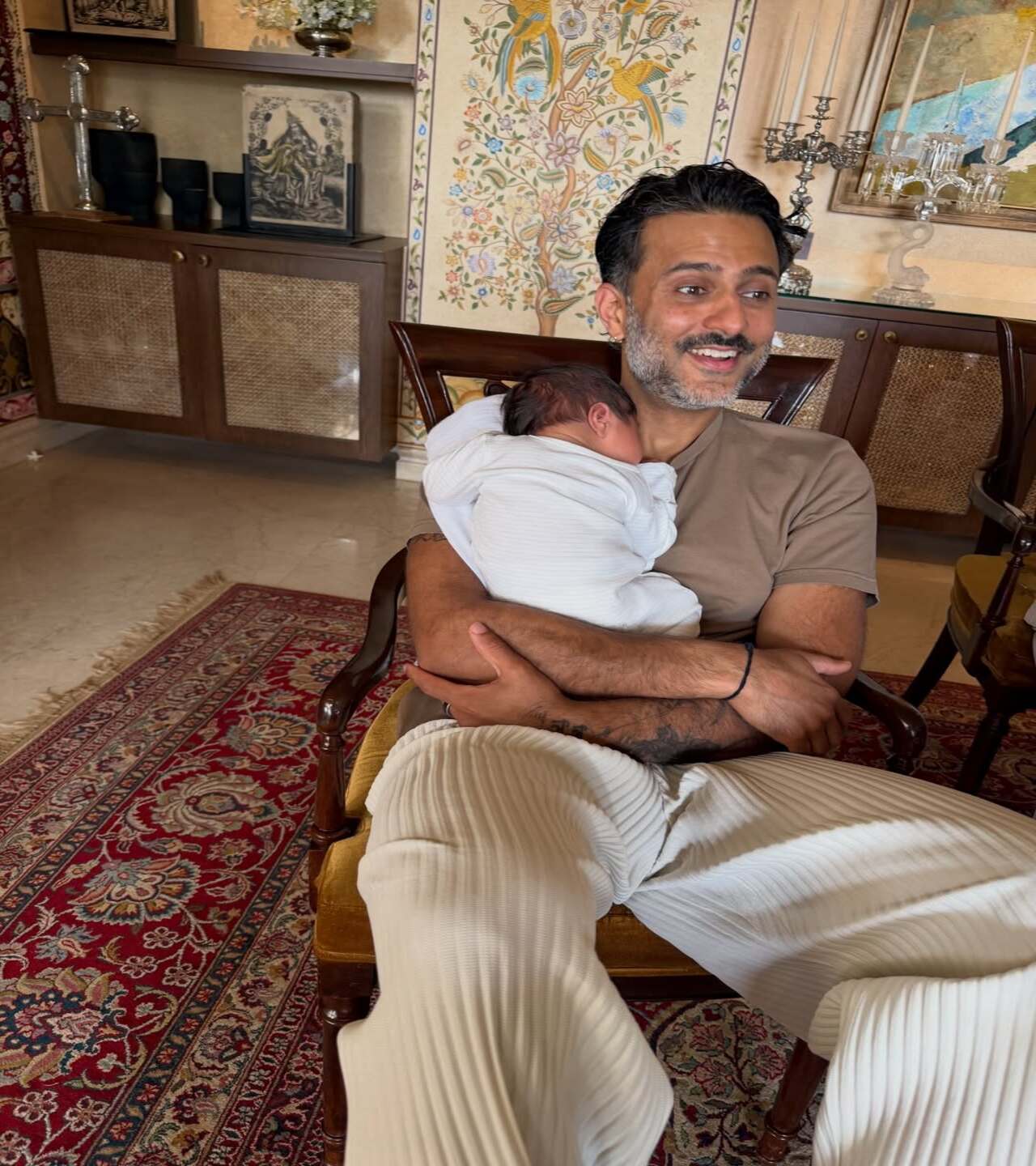 Anand Ahuja is captured in a candid moment when he is cradling the baby close to his chest and rocking him gently